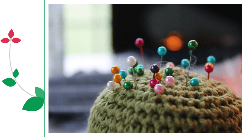 A crocheted hat with pins on top of it.