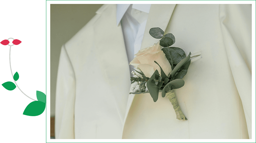 A man in white suit and tie with a flower.