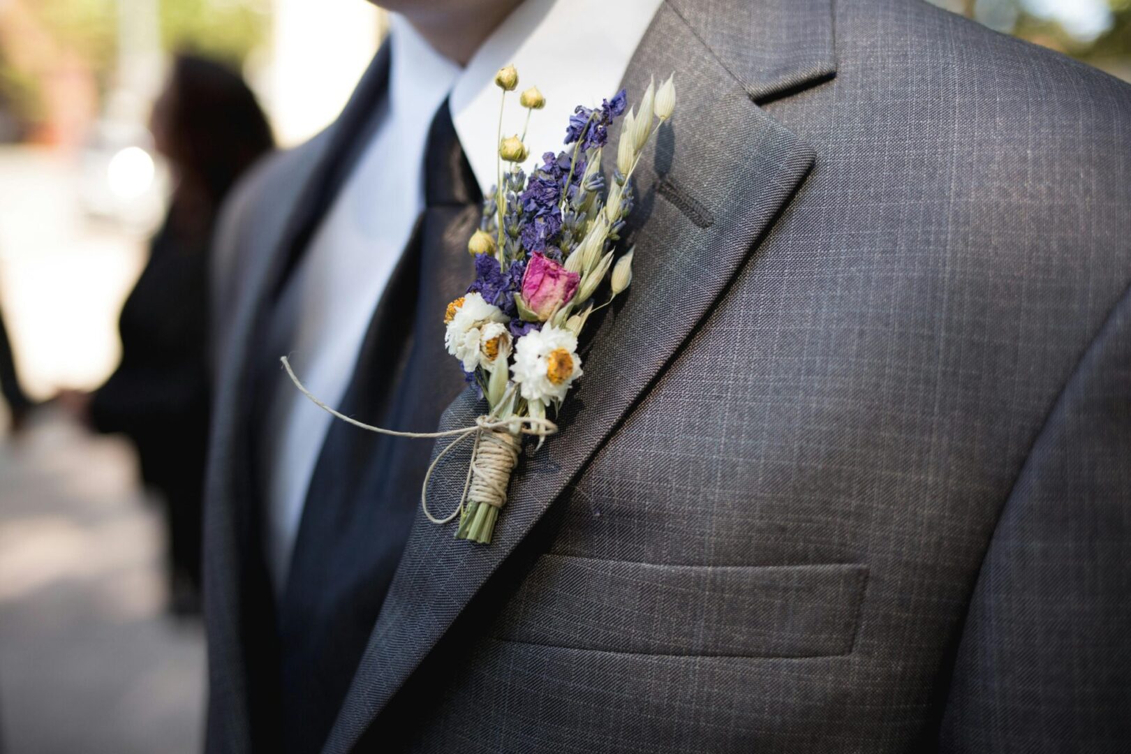 A man in a suit and tie with flowers on his lapel.